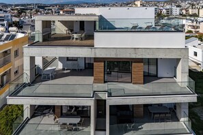 A modern multi-story building with outdoor seating areas and glass railings. - 103 Piliou - City View Balcony & Shared Rooftop Pool (Limassol)