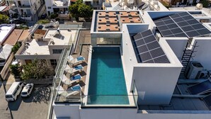 Una azotea con piscina, paneles solares y balaustrada de vidrio.