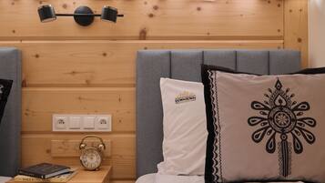 Ein Hotelzimmer mit einem Holzkopfteil, Nachttischlampen, einer Uhr und einem Bett mit gemusterten Kissen.