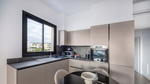 Eine moderne Küche mit einem großen Fenster, einem Esstisch mit Stühlen und integrierten Geräten.