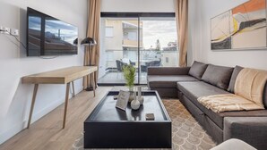 Ein modernes Wohnzimmer mit Sofa, Couchtisch, Fernseher und großem Fenster.