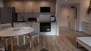 Una cocina moderna con armarios de madera, un refrigerador, microondas, horno y una zona de comedor con una mesa redonda y sillas.