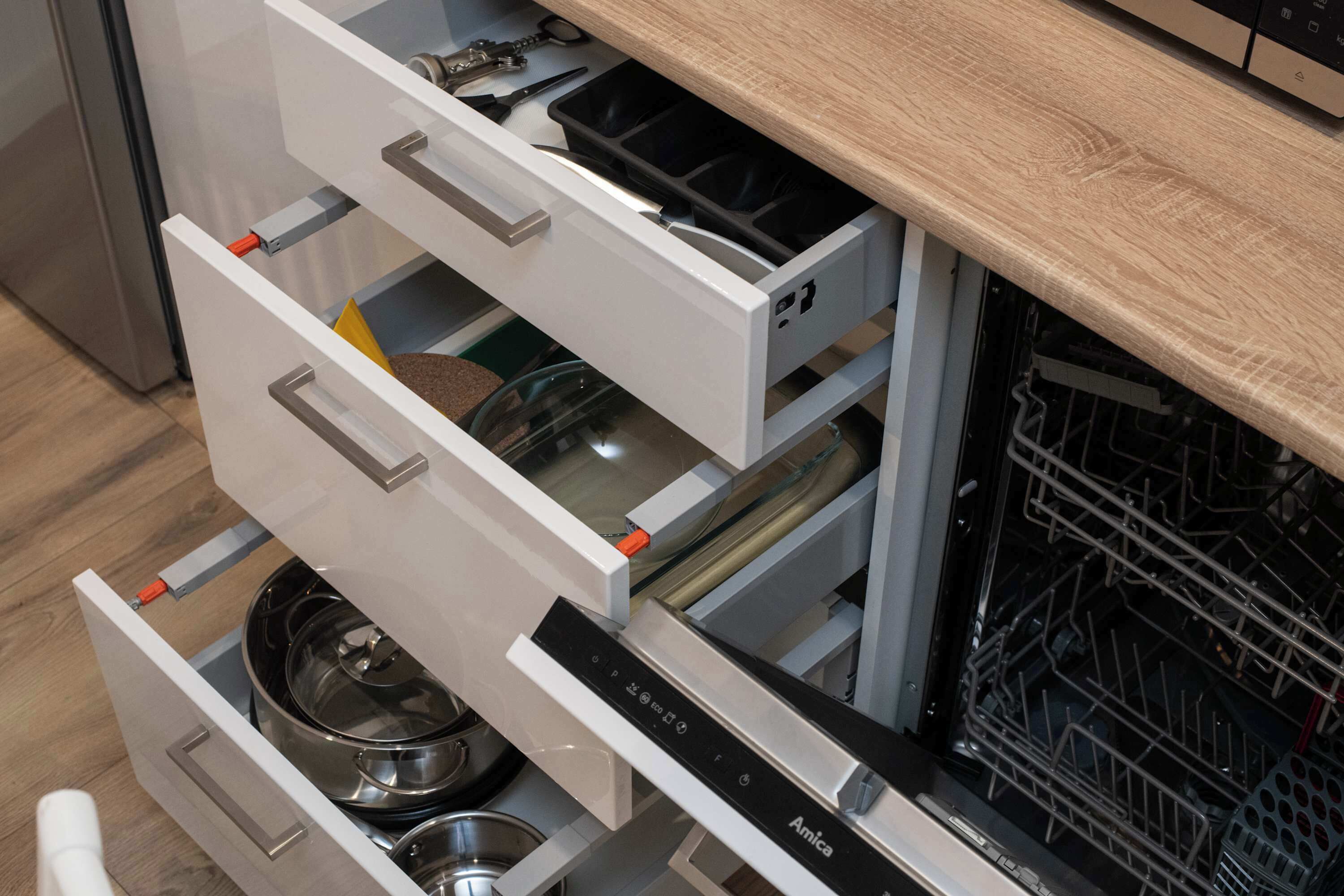 A kitchen with a built-in dishwasher and a stainless steel refrigerator.