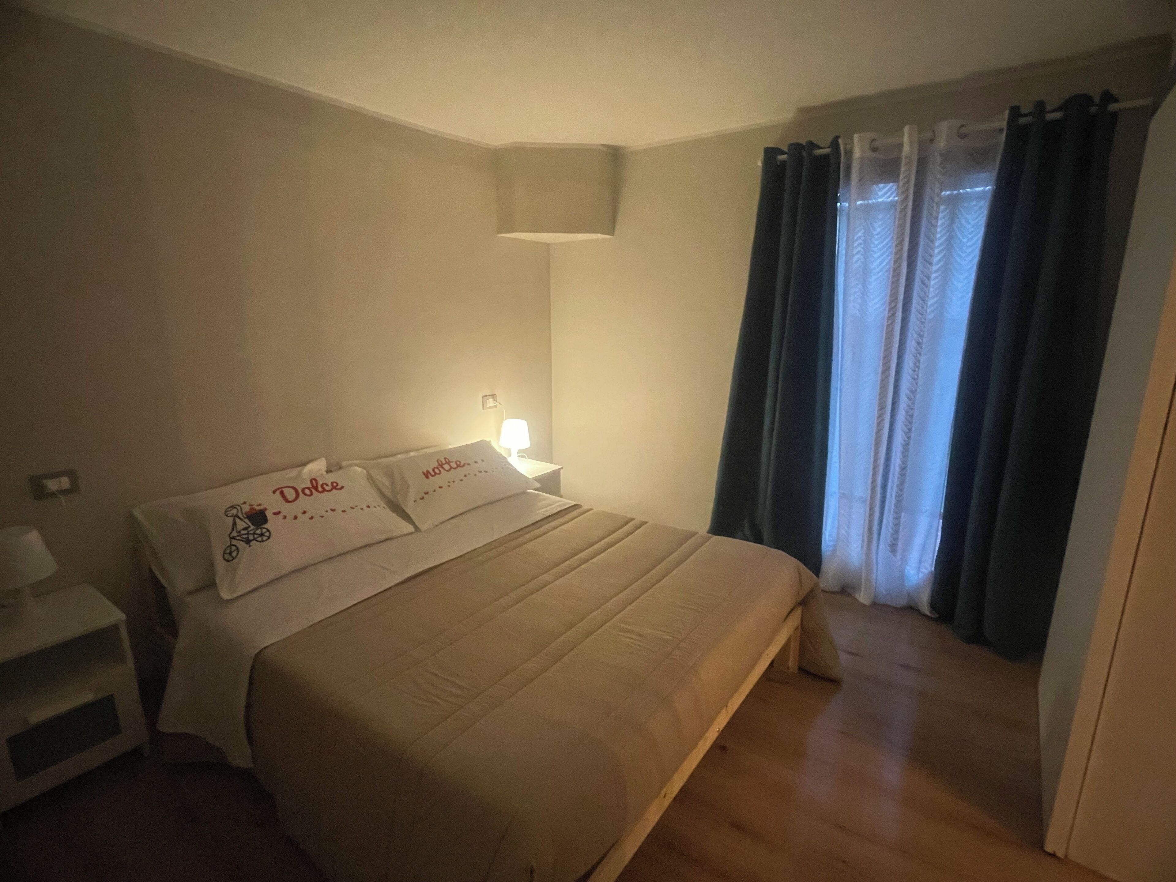 A bedroom with a bed, bedside tables, a lamp, and a window with curtains.