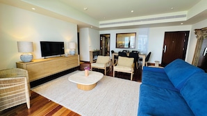 Una sala de estar moderna con un sofá azul, un televisor, un aparador de madera y un comedor con sillas y una mesa.