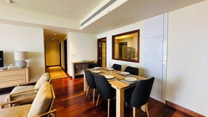 Un comedor con una mesa de madera, sillas negras y un espejo en la pared.