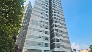 Un edificio de gran altura con diseño moderno, que cuenta con un amplio frente de vidrio y múltiples balcones.