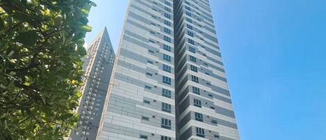 A high-rise building with a modern design, featuring a large glass facade and multiple balconies.