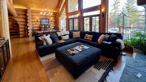 Ein rustikales Blockhaus-Interieur mit einer großen Couch, einem Couchtisch und einem Kamin.