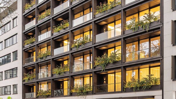 Un immeuble à plusieurs étages doté de balcons, chacun étant agrémenté de plantes.