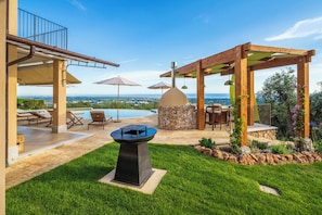 A backyard with a pool, outdoor seating, and a stone wall. - Villa Palatina - Vivere Housing (Toscana)