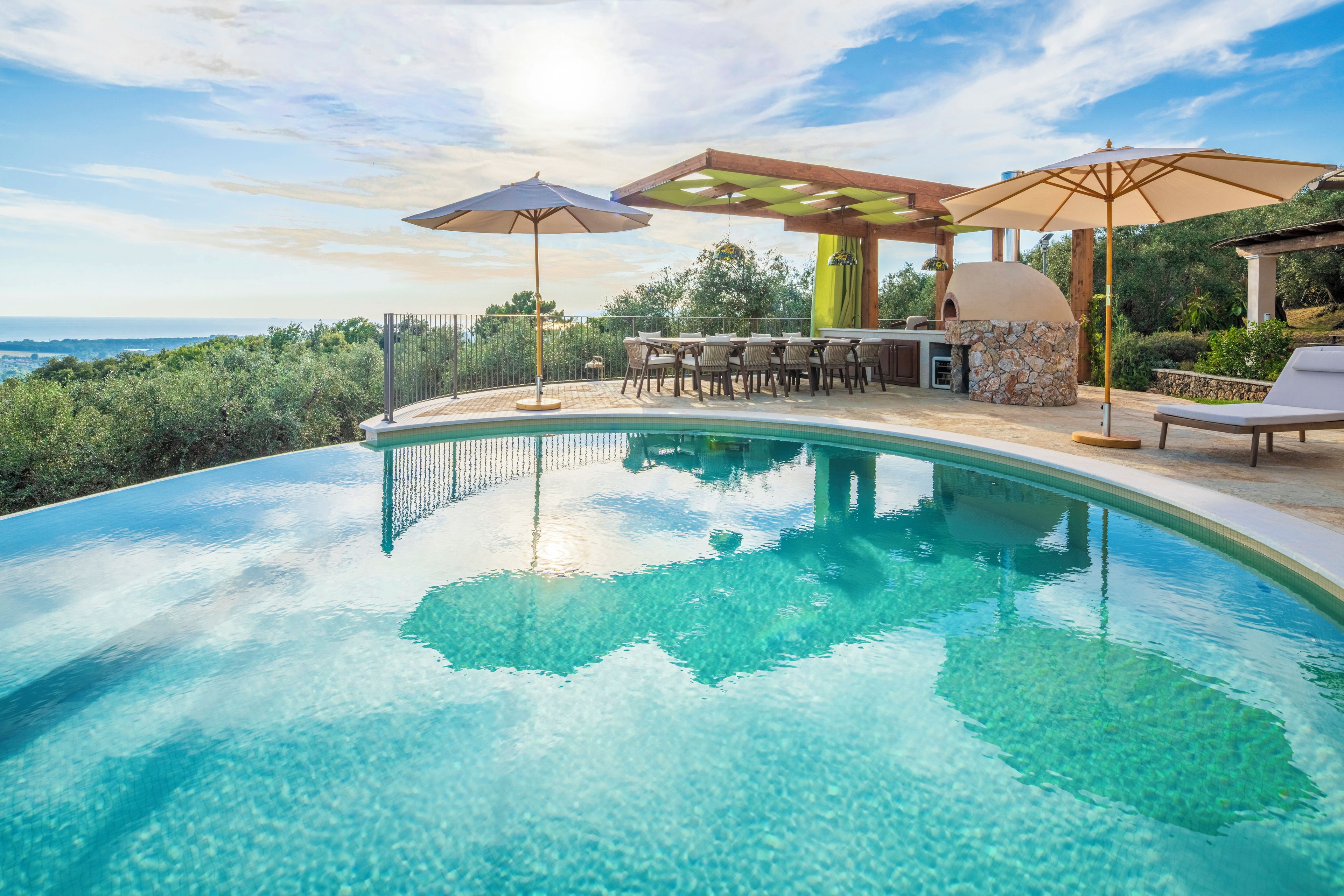 A swimming pool with a curved edge, surrounded by outdoor seating and a barbecue area.