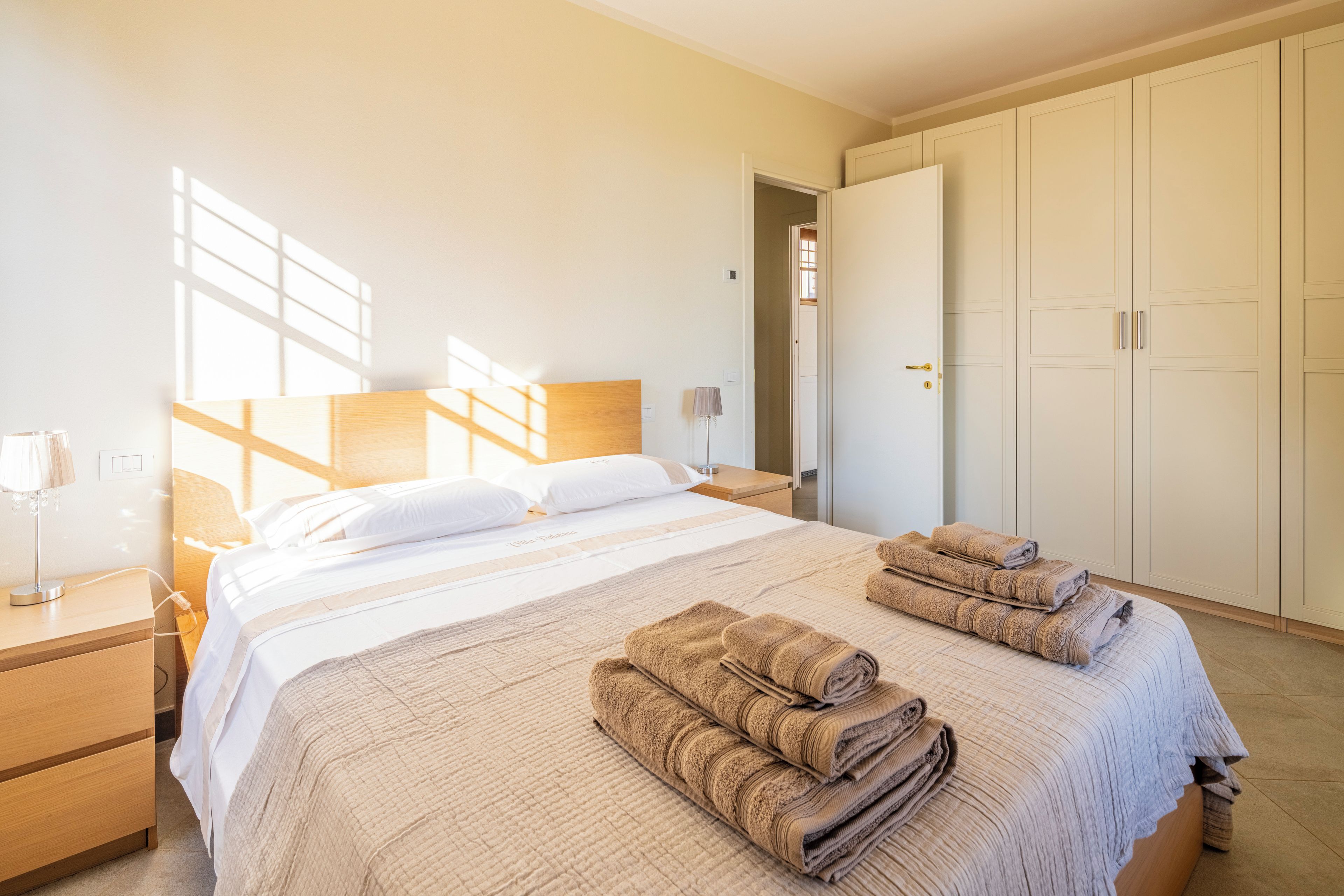 Une chambre d’hôtel avec un lit, une table de chevet, une lampe, une armoire et une fenêtre.