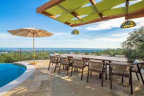 An outdoor dining area with a pool, wooden furniture, and a view of the landscape. - Villa Palatina - Vivere Housing (Toscana)