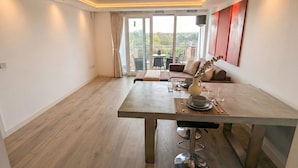 A modern dining area with a wooden table, bar stools, and a view of the outdoors. - Kew Connection -
Relax in this light airy river view apartment. (Brentford)