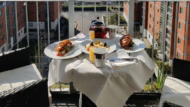 A balcony table with breakfast items, a city view, and modern buildings. - Kew Connection -
Relax in this light airy river view apartment. (Brentford)