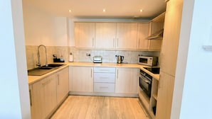 A compact kitchen with light wood cabinets, a built-in oven, a microwave, and a toaster. - Kew Connection -
Relax in this light airy river view apartment. (Brentford)