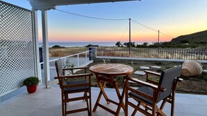 Une terrasse couverte, dotée d’une table et de chaises, qui offre une vue sur une plage et l’océan.