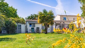 Una propiedad residencial con fachada blanca, techo de tejas y un patio cercado con una palmera.