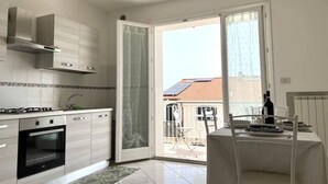 A modern kitchen with a gas stove, oven, and a sliding glass door leading to a balcony. - P081 - Porto Recanati, new three-room apartment with balcony (Porto Recanati)