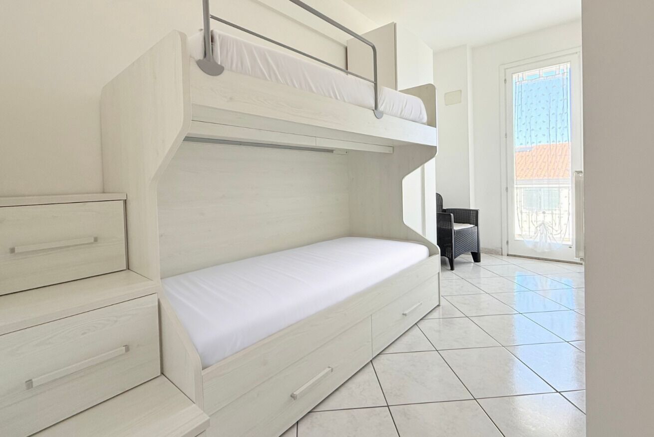 A bunk bed room with a lower bunk, a drawer, and a chair.