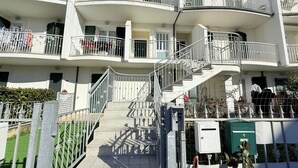 A multi-story residential building with balconies, a central staircase, and a gated entrance. - P081 - Porto Recanati, new three-room apartment with balcony (Porto Recanati)