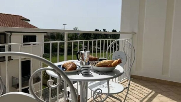 A balcony with a table set for breakfast, including croissants and a coffee pot. - P081 - Porto Recanati, new three-room apartment with balcony (Porto Recanati)