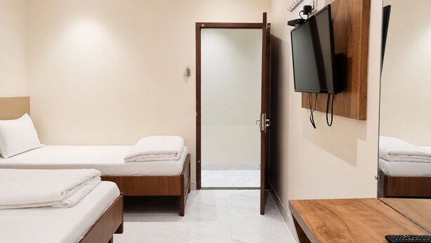 Ein Hotelzimmer mit zwei Betten, einem Fernseher und einem Holztisch.