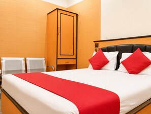 A hotel room with a bed, a wardrobe, and a seating area with chairs. - Hotel Volga 2 (Mumbai)