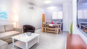 Una sala moderna con un sofá, una mesa de centro y un comedor con una mesa y sillas.
