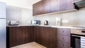 Una cocina con armarios de madera oscura, salpicadero de azulejos blancos y electrodomésticos modernos como tostadora, microondas, hervidor y cafetera.