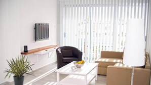 Una sala de estar moderna con un sofá, una mesa de centro, un televisor montado en la pared y una planta en maceta.