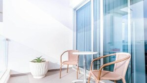 Ein Balkon mit zwei Korbstühlen und einem kleinen weißen Topf mit einer Pflanze.