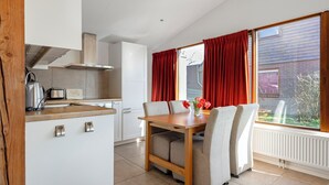Une cuisine moderne avec des armoires blanches, une table en bois et des chaises.