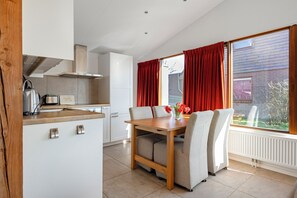 Een moderne keuken met witte kasten, een houten tafel en stoelen.