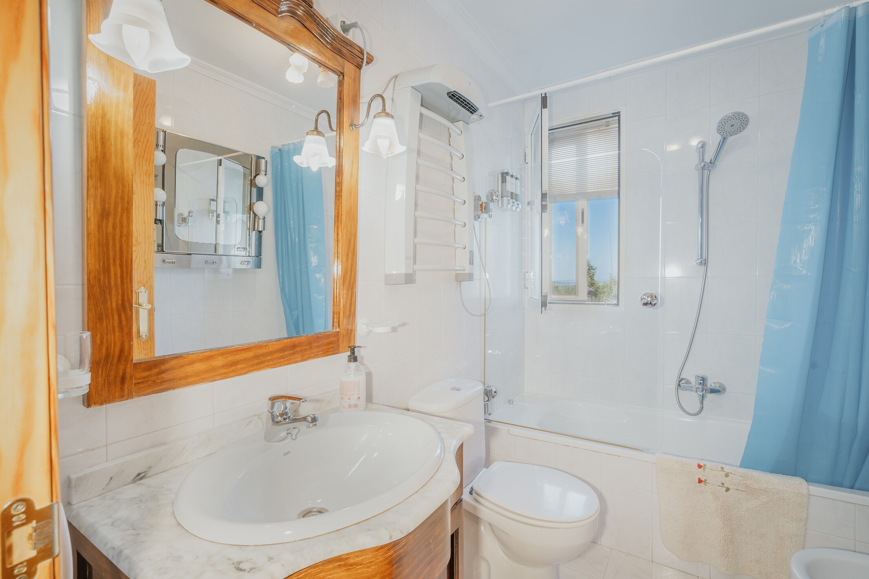 Un baño con lavamanos, espejo, ducha e inodoro.