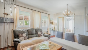 A living room with a sofa, a coffee table, and a chandelier. - La Rosa De Los Vientos, Villa with Pool & Hot Tub in Sierra de Guadarrama (Los Ángeles de San Rafael)