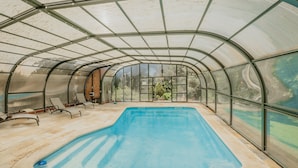 A covered swimming pool with a glass ceiling, lounge chairs, and a view of greenery outside. - La Rosa De Los Vientos, Villa with Pool & Hot Tub in Sierra de Guadarrama (Los Ángeles de San Rafael)