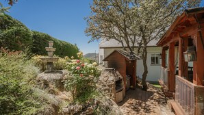 A stone water feature, a wooden structure, and a garden with flowering plants. - La Rosa De Los Vientos, Villa with Pool & Hot Tub in Sierra de Guadarrama (Los Ángeles de San Rafael)