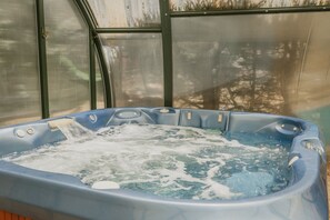 A hot tub with water flowing, surrounded by a greenhouse structure.