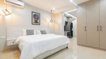 A modern bedroom with a large bed, a wardrobe, a wall-mounted air conditioner, and a painting.