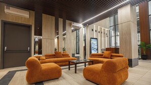 A modern lobby with a seating area featuring orange sofas and a coffee table. - Sky Suites BRAVIA RESIDENCE OSU (Accra)