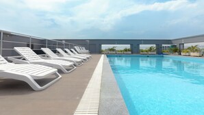 A swimming pool with white lounge chairs and a clear sky. - Sky Suites BRAVIA RESIDENCE OSU (Accra)