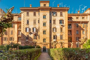 A multi-story building with a central entrance, surrounded by well-maintained hedges and trees. - Testaccio Skyline (Roma)