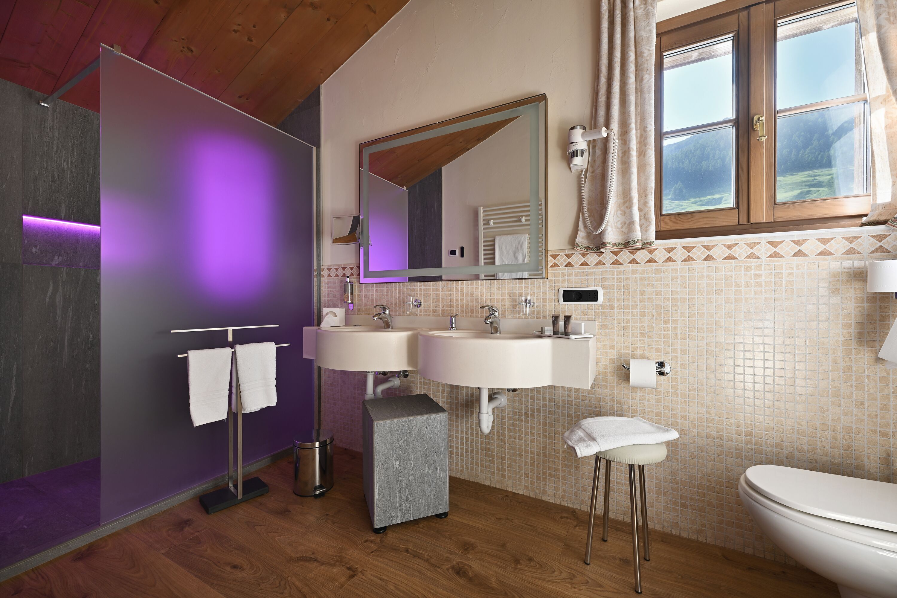 A modern bathroom with two sinks, a large mirror, and a shower.