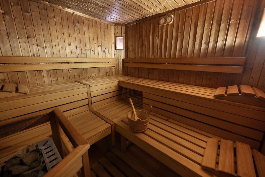 Un sauna avec des bancs en bois et un seau en bois.