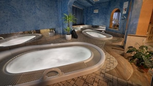Un espace de détente avec plusieurs bains à remous, un grand miroir et une plante en pot.
