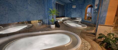 Un área de spa con varios jacuzzis, un espejo grande y una planta en maceta.