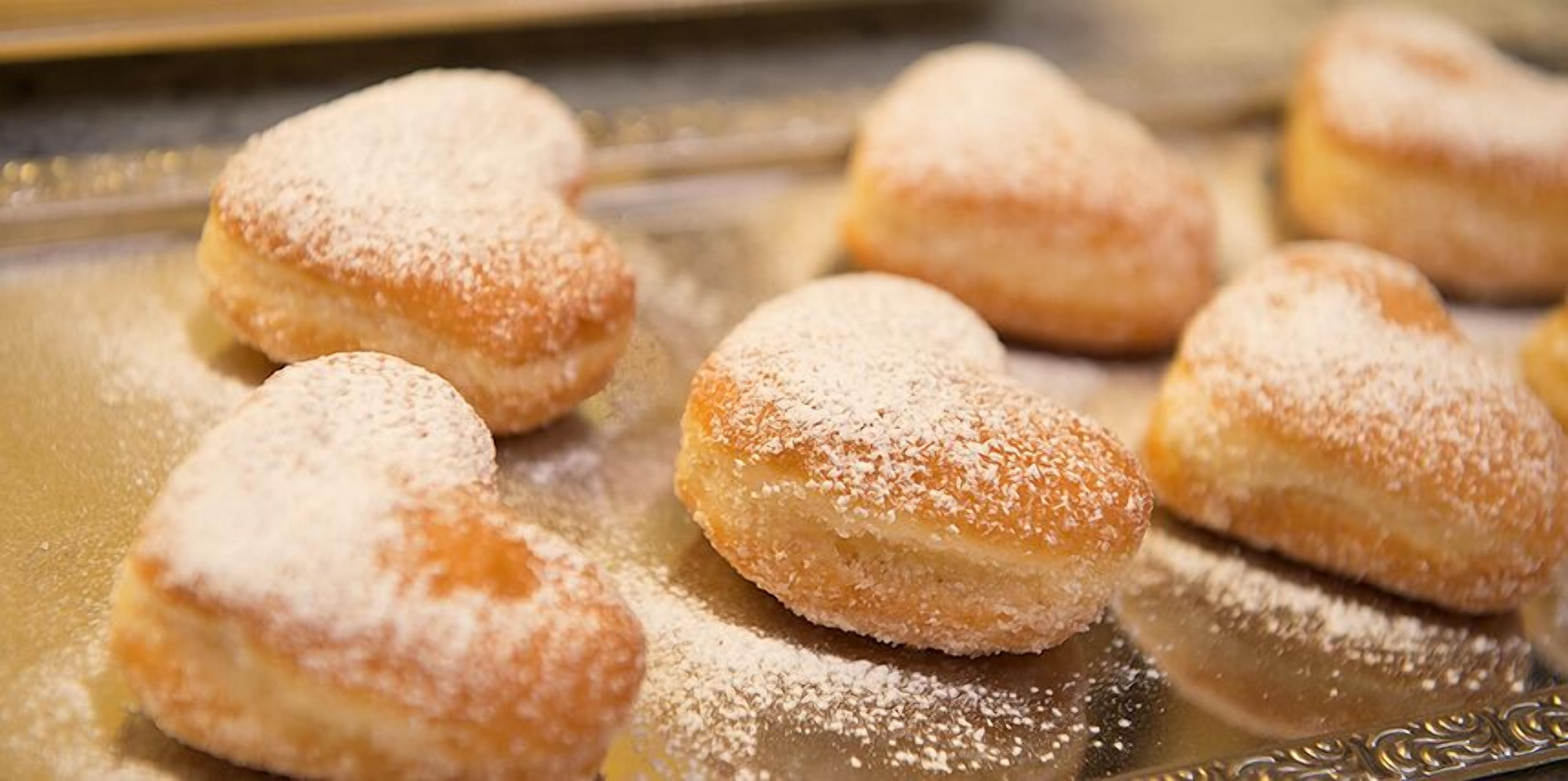 Un plateau de petits gâteaux en forme de cœur, saupoudrés de sucre glace.