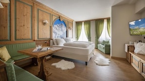 Une pièce confortable avec un lit, un canapé vert, une table en bois et un téléviseur.